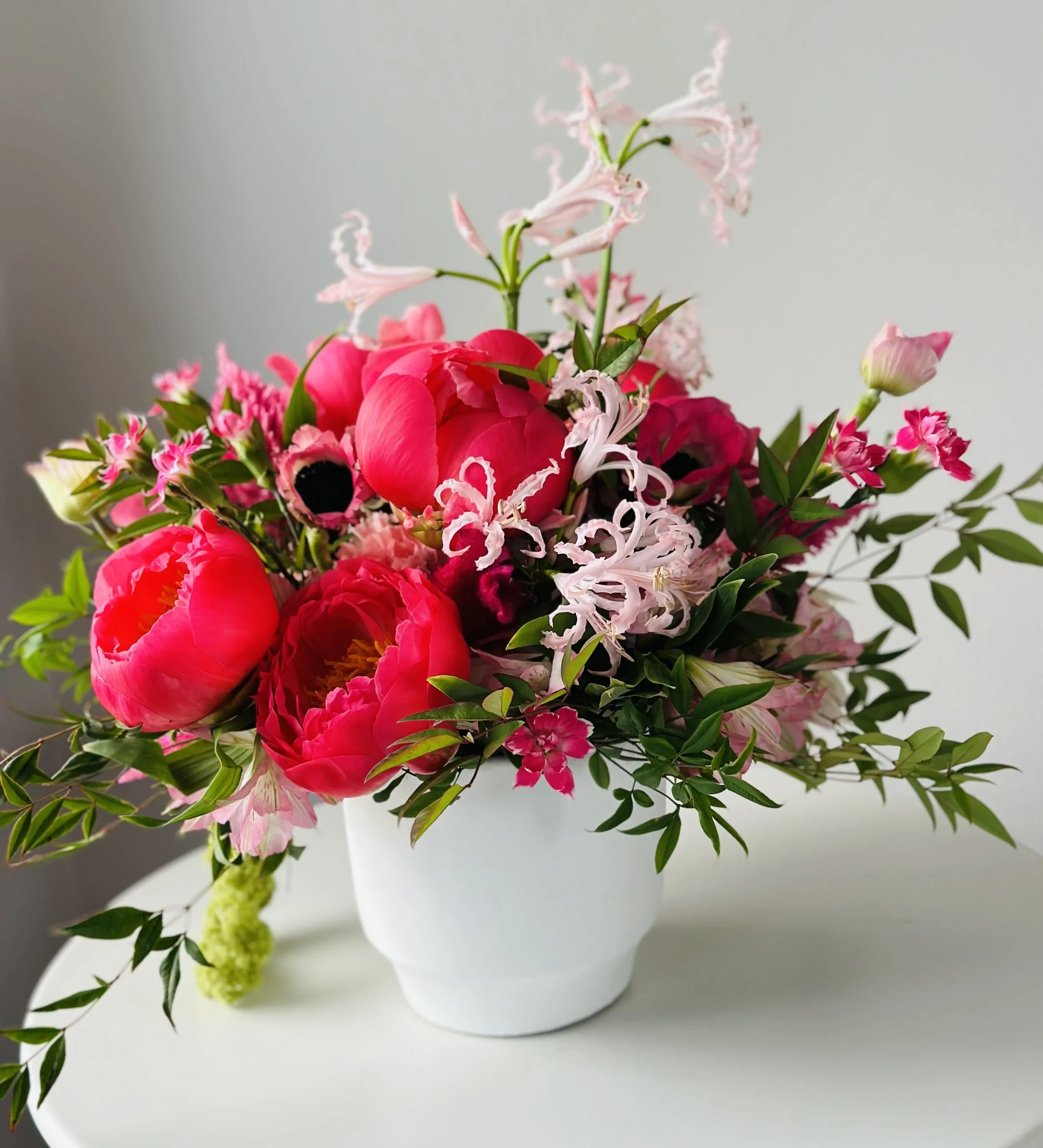 Vase of pink and red peonies with greenery